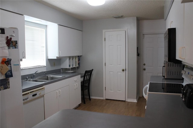 kitchen with a textured ceiling, white cabinetry, sink, and white appliances