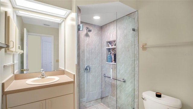 bathroom with vanity, a skylight, a shower with shower door, and toilet