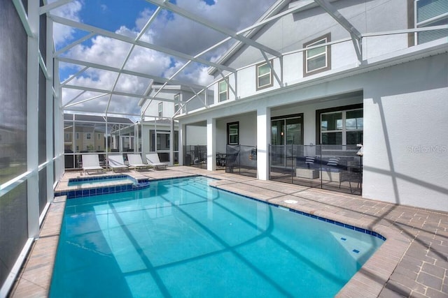 view of swimming pool with glass enclosure, an in ground hot tub, and a patio