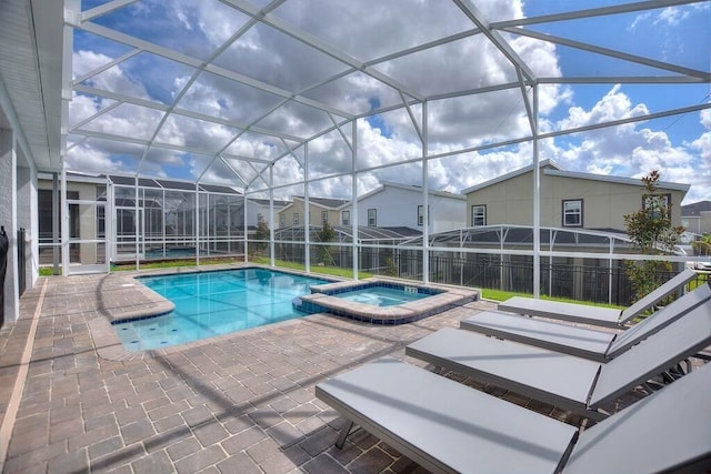 view of swimming pool with an in ground hot tub, a patio area, and glass enclosure