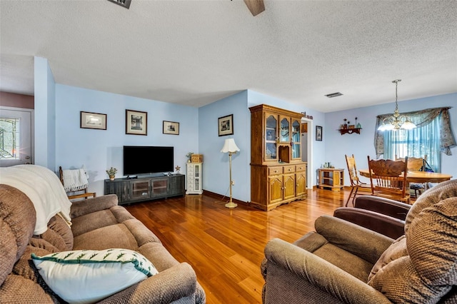 living room featuring dark wood-type flooring, a chandelier, and a textured ceiling