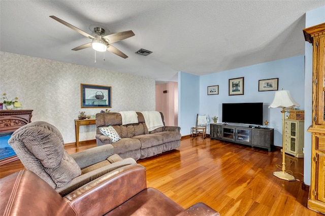 living room featuring ceiling fan, wood-type flooring, and a textured ceiling