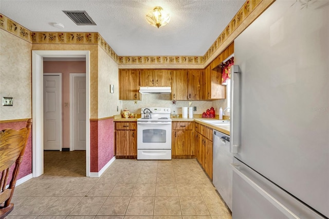 kitchen with dishwasher, sink, fridge, electric range, and a textured ceiling