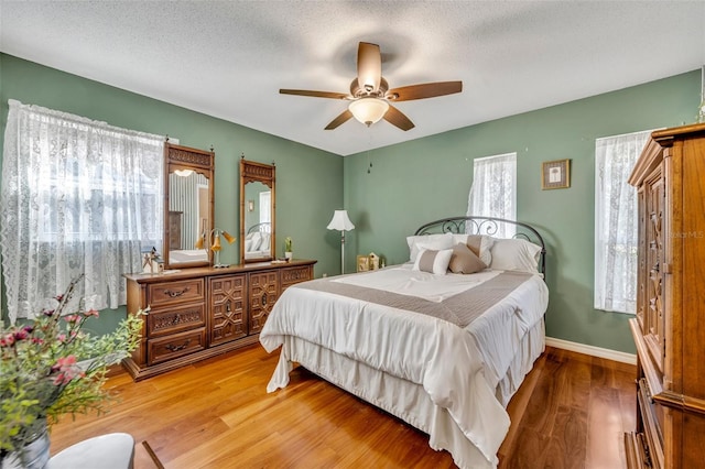 bedroom with hardwood / wood-style flooring, a textured ceiling, and ceiling fan