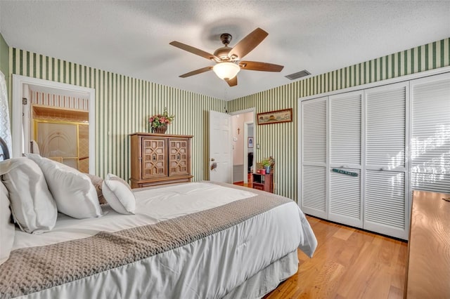 bedroom with light hardwood / wood-style floors, a textured ceiling, ceiling fan, and a closet