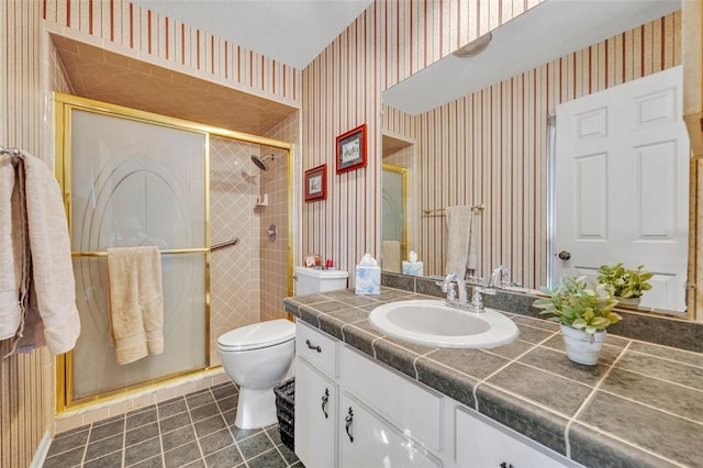 bathroom featuring a shower with door, vanity, tile patterned floors, and toilet