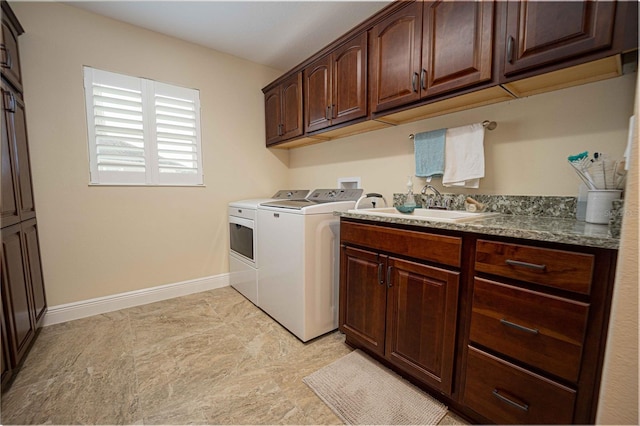 clothes washing area with cabinets, washer and dryer, and sink