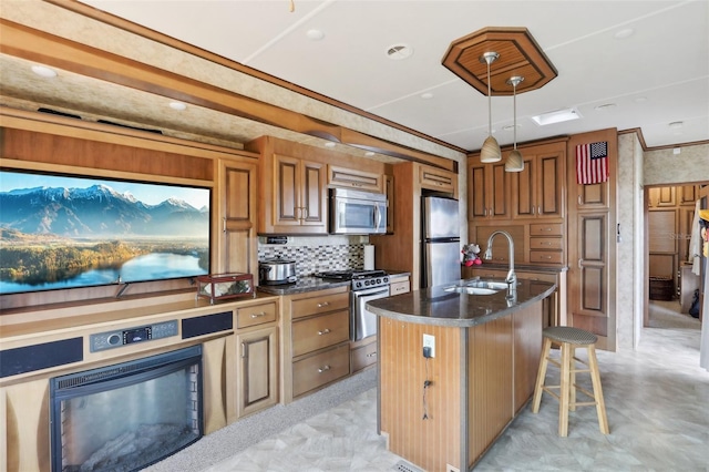 kitchen with pendant lighting, sink, a kitchen island with sink, stainless steel appliances, and a kitchen breakfast bar