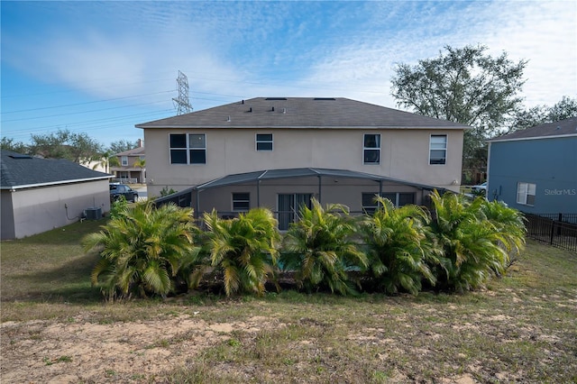 back of house with a lawn, central AC unit, and glass enclosure