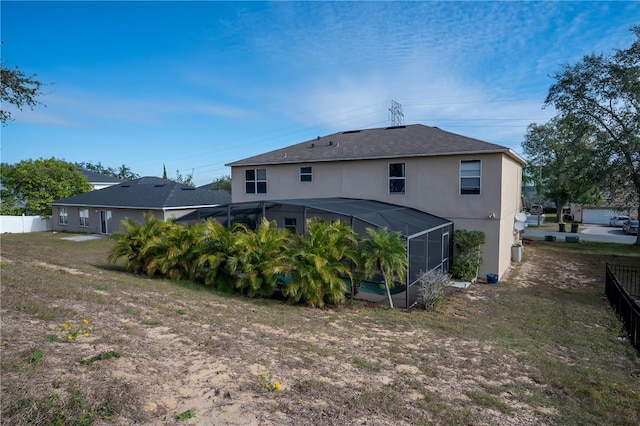 back of property featuring a lanai and a lawn