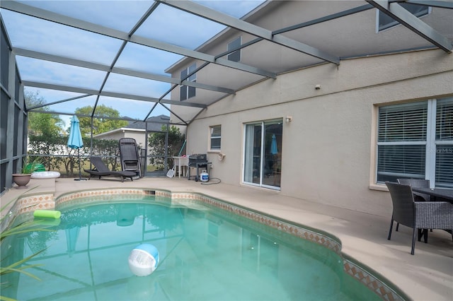 view of pool featuring glass enclosure, area for grilling, and a patio area