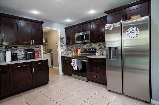 kitchen featuring decorative backsplash, light tile patterned floors, dark brown cabinetry, and stainless steel appliances