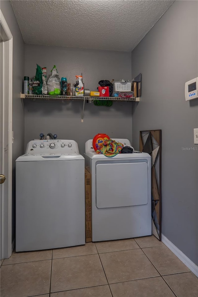 clothes washing area featuring light tile patterned floors, separate washer and dryer, and a textured ceiling