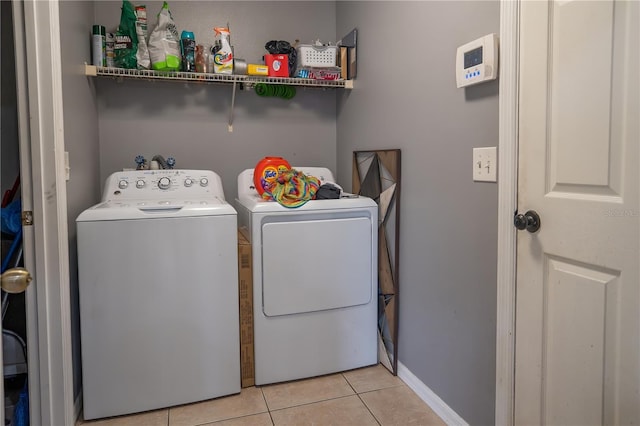 laundry area with separate washer and dryer and light tile patterned floors