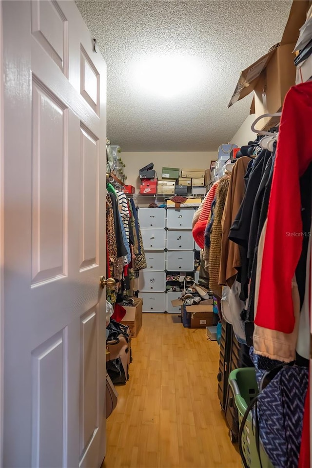 walk in closet with light hardwood / wood-style flooring