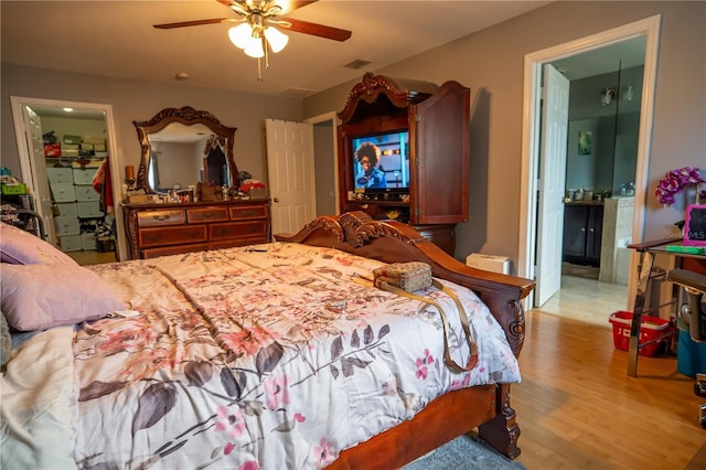 bedroom featuring ceiling fan, light hardwood / wood-style flooring, and a walk in closet