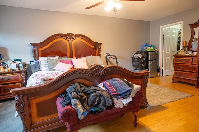 bedroom featuring ceiling fan, stainless steel fridge, and hardwood / wood-style flooring