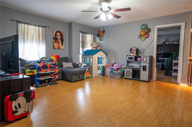 recreation room with ceiling fan, light wood-type flooring, and a healthy amount of sunlight