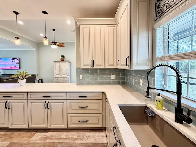 kitchen featuring sink, tasteful backsplash, pendant lighting, ceiling fan, and white cabinets