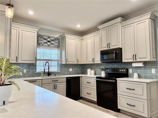 kitchen with tasteful backsplash, decorative light fixtures, sink, and black appliances