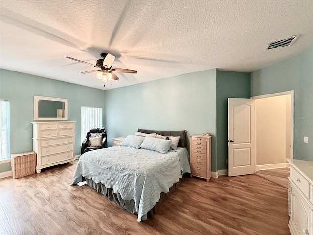 bedroom with ceiling fan, a textured ceiling, and light wood-type flooring