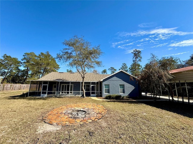 view of front of house featuring a sunroom, an outdoor fire pit, and a front lawn