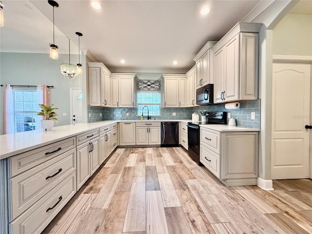 kitchen with pendant lighting, kitchen peninsula, light hardwood / wood-style floors, and black appliances