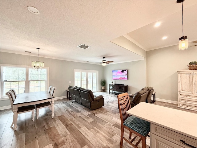 living room featuring crown molding, light hardwood / wood-style flooring, a textured ceiling, and ceiling fan with notable chandelier