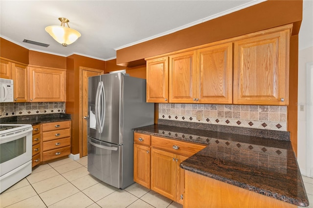 kitchen featuring light tile patterned floors, crown molding, white appliances, tasteful backsplash, and dark stone counters