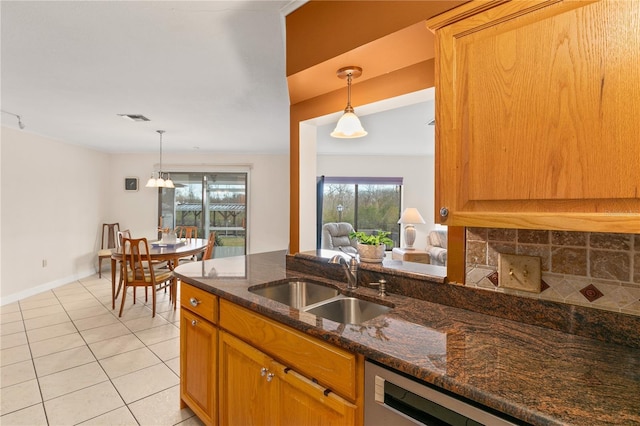 kitchen featuring light tile patterned flooring, sink, tasteful backsplash, hanging light fixtures, and dark stone counters