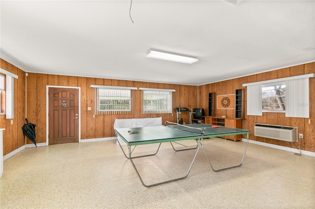 game room featuring wood walls, a wall mounted AC, and a wealth of natural light