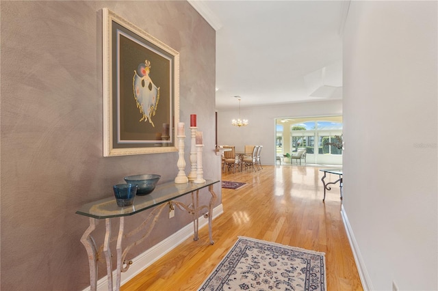 hall with hardwood / wood-style floors, crown molding, and a chandelier