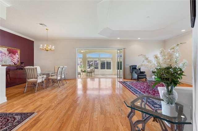 dining space with a tray ceiling, hardwood / wood-style flooring, ornamental molding, and a chandelier