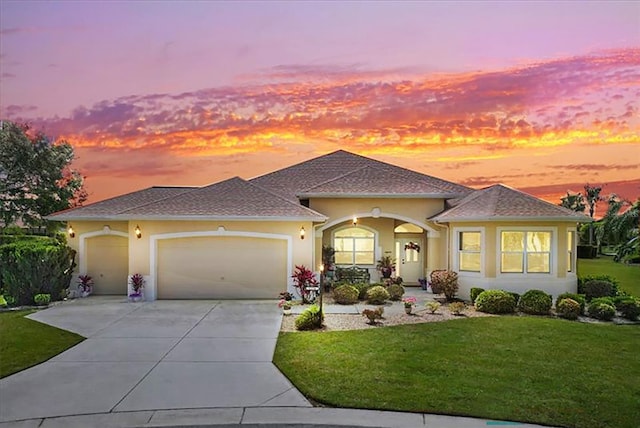 view of front facade with concrete driveway, a lawn, an attached garage, and stucco siding