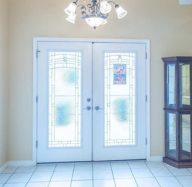 entryway featuring french doors, a notable chandelier, baseboards, and tile patterned floors