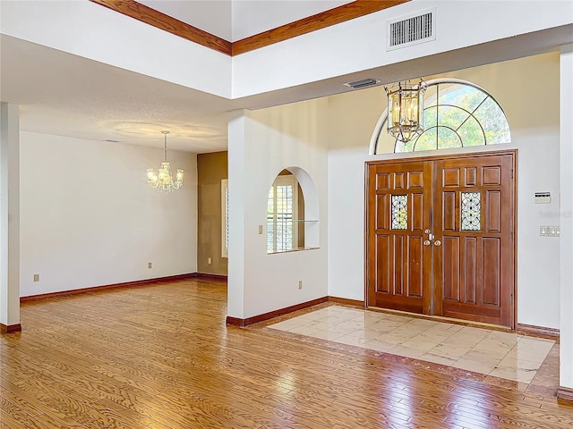 entryway featuring an inviting chandelier, a towering ceiling, and light hardwood / wood-style floors