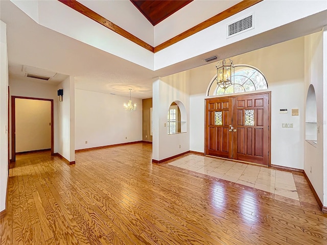 foyer entrance featuring an inviting chandelier, light hardwood / wood-style flooring, and a high ceiling