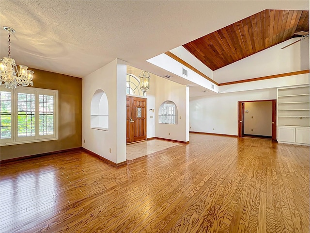 unfurnished living room featuring built in shelves, lofted ceiling, wood ceiling, a textured ceiling, and light wood-type flooring