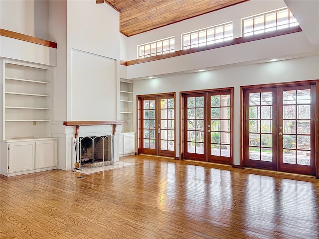 unfurnished living room with a towering ceiling, built in features, and french doors