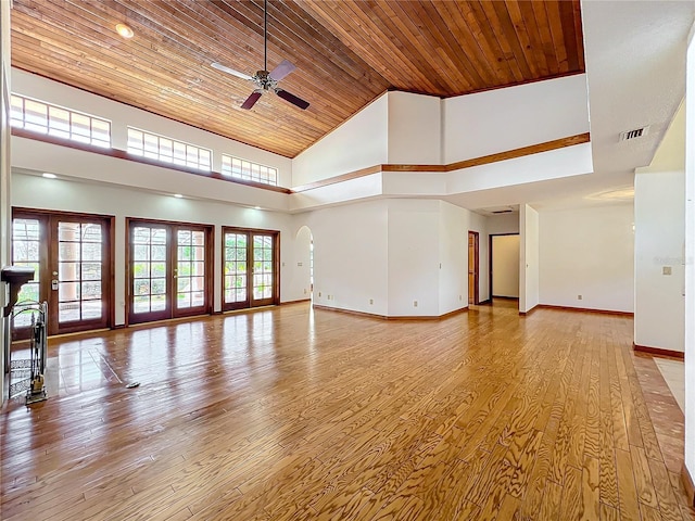 unfurnished living room with a high ceiling, light wood-type flooring, wood ceiling, and french doors