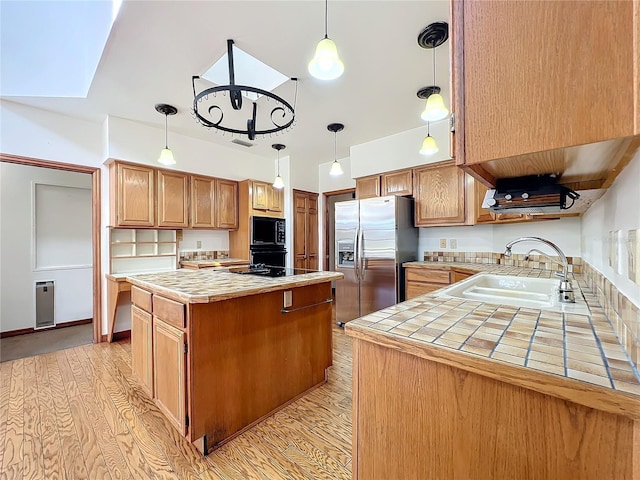 kitchen featuring a kitchen island, sink, light hardwood / wood-style flooring, and black appliances