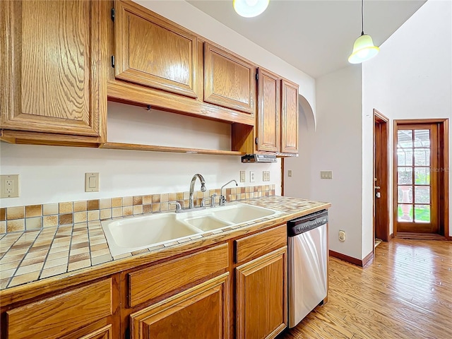 kitchen featuring sink, tile countertops, decorative light fixtures, light wood-type flooring, and stainless steel dishwasher