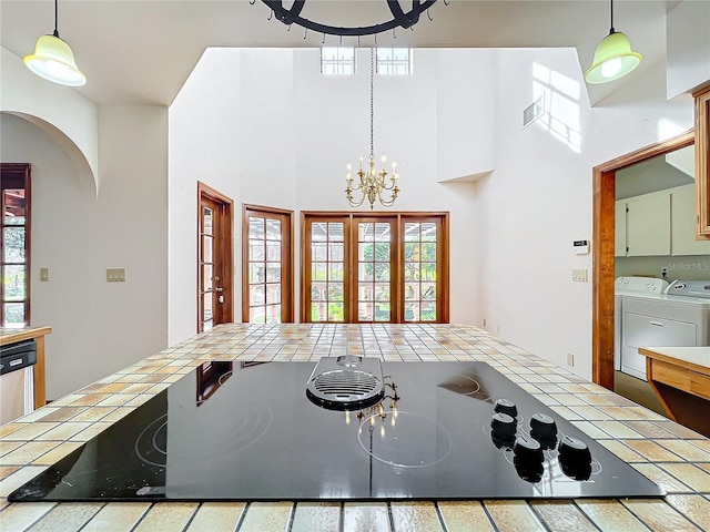 kitchen featuring washing machine and clothes dryer, tile countertops, hanging light fixtures, and a notable chandelier