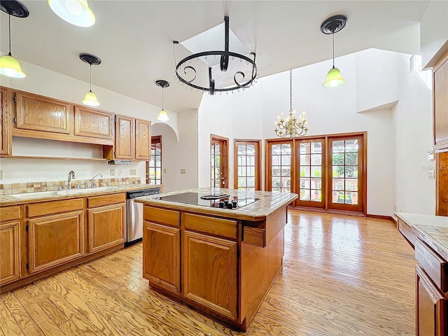 kitchen featuring black electric stovetop, decorative light fixtures, tile countertops, stainless steel dishwasher, and light wood-type flooring