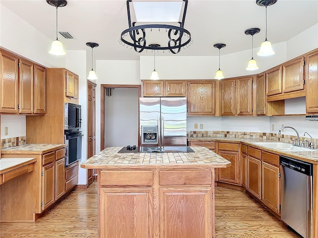 kitchen featuring sink, light wood-type flooring, a kitchen island, and black appliances