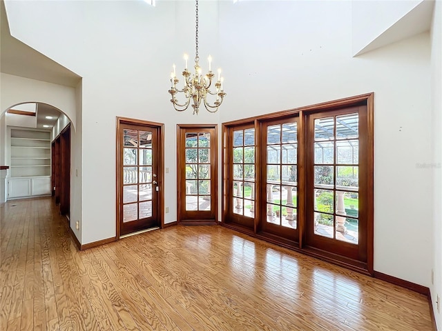 doorway with a wealth of natural light, light hardwood / wood-style floors, and a high ceiling