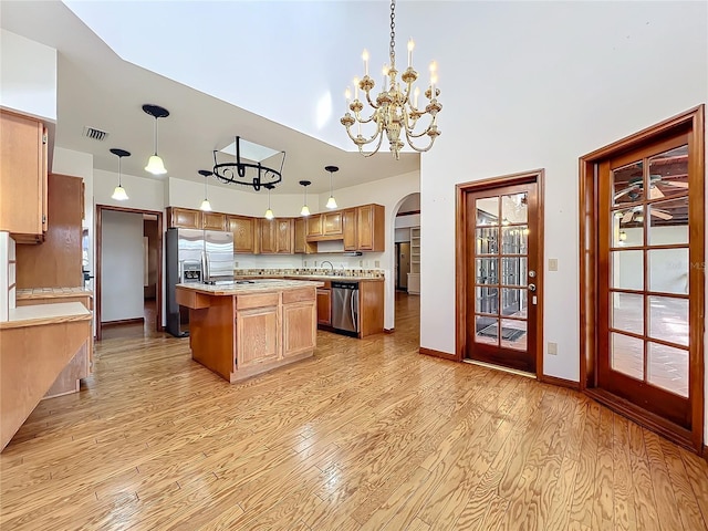 kitchen featuring stainless steel appliances, a center island, light hardwood / wood-style flooring, and decorative light fixtures