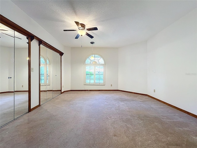 unfurnished bedroom with light carpet, a textured ceiling, and ceiling fan