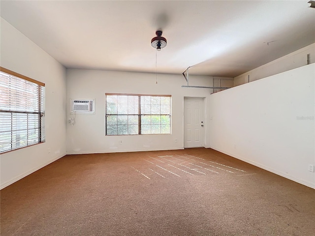 empty room with a wall mounted air conditioner, carpet flooring, and plenty of natural light