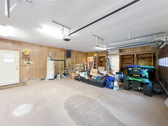 garage featuring a garage door opener, wooden walls, and electric water heater